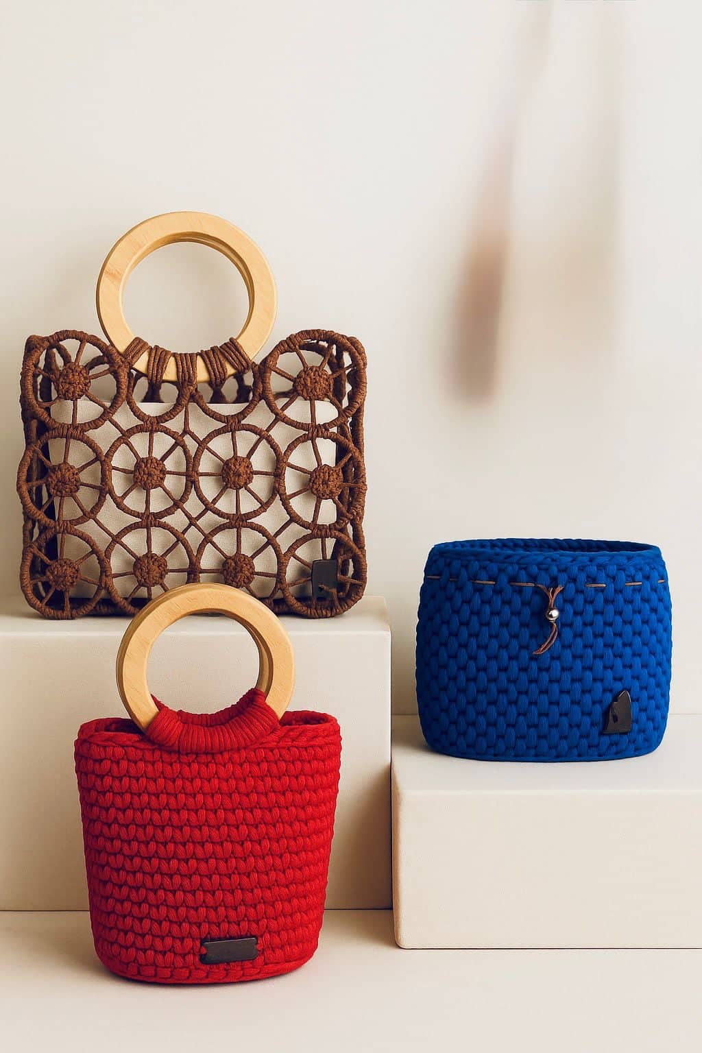 Carteras artesanales roja, café y azul con asas de madera.