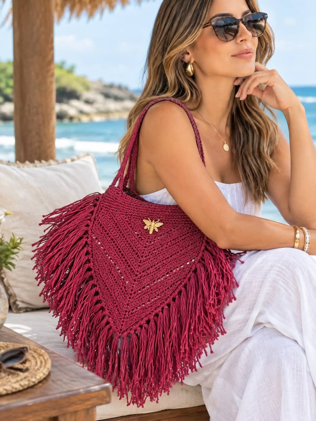 Modelo con cartera roja de flecos frente al mar.